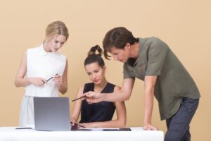 two woman and one man looking at the laptop