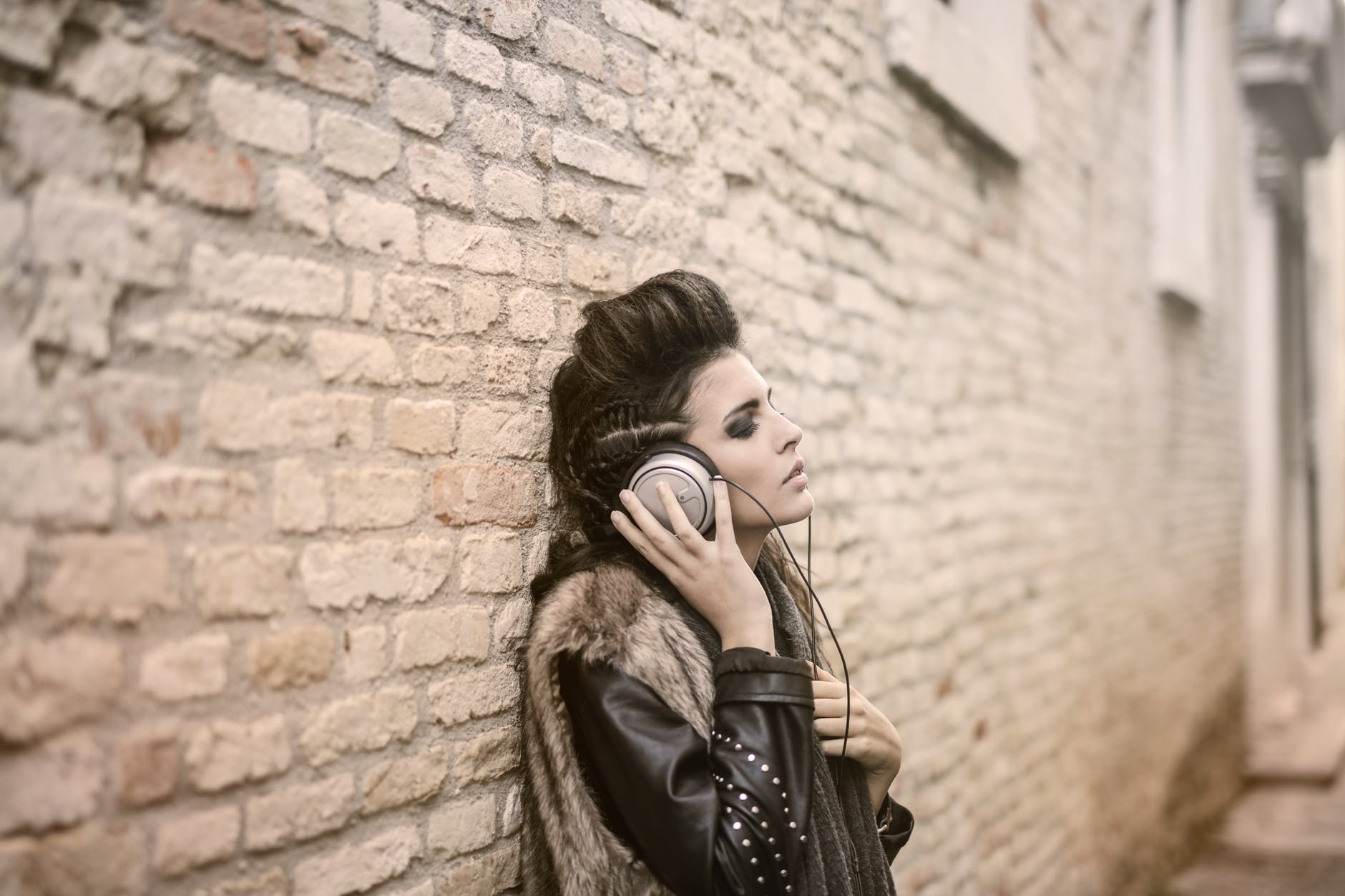 woman in stylish wear listening to music in headphones