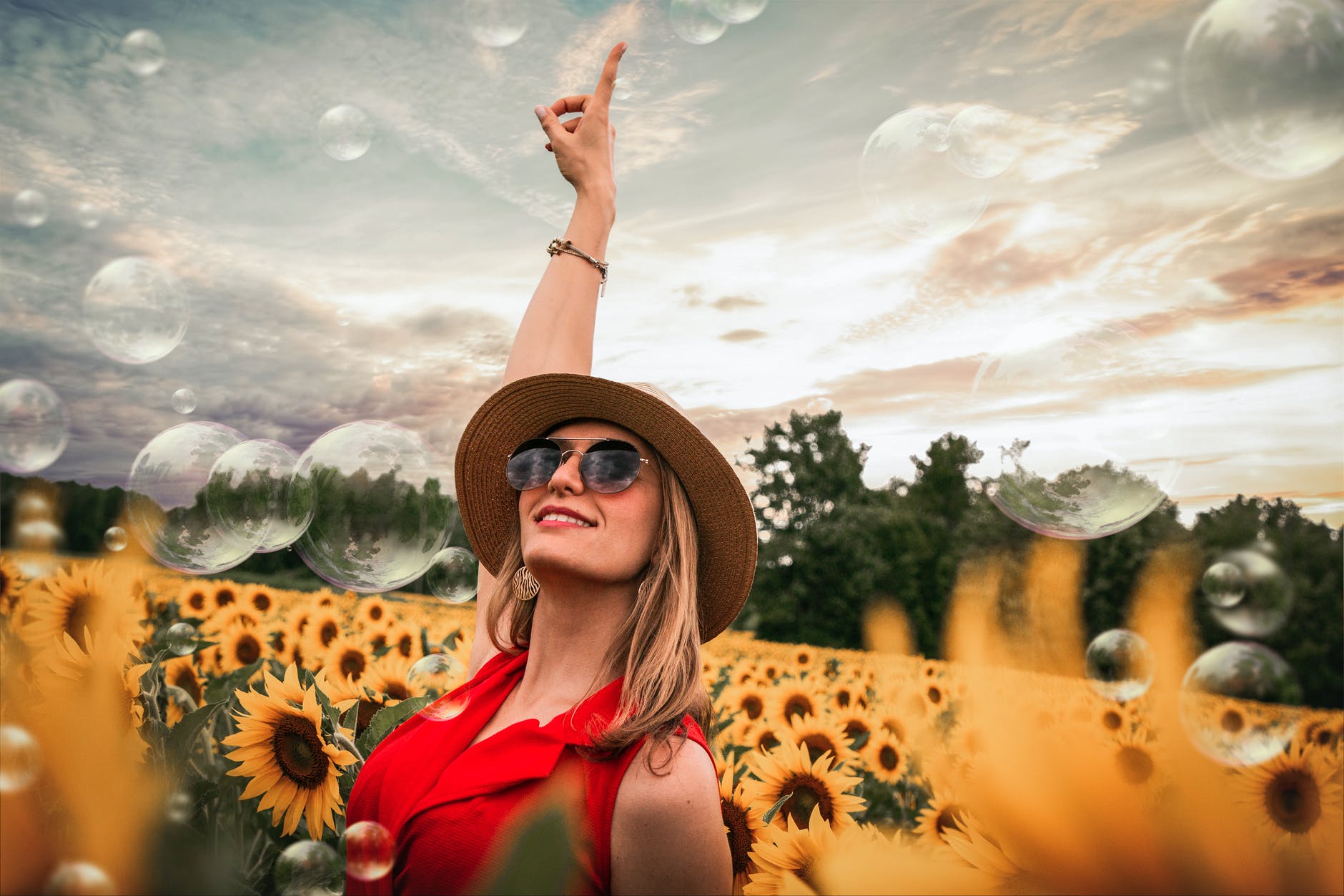 woman surrounded by sunflowers raising hand